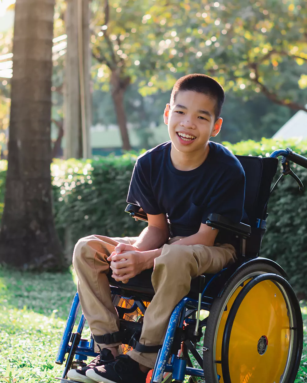 A disabled teenage boy outdoors, he is happy