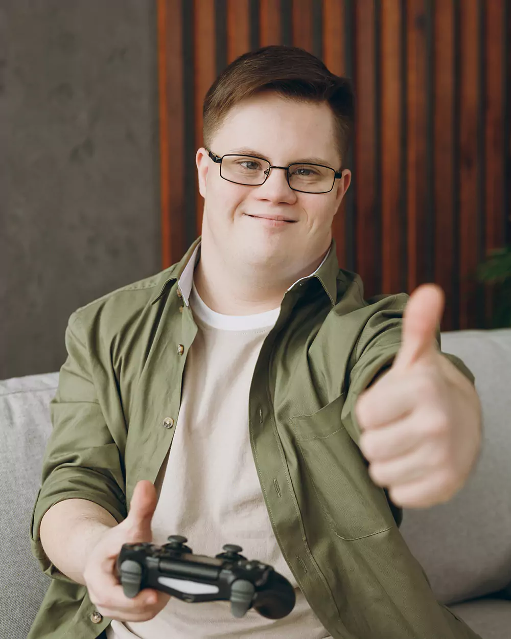 A down syndrome man giving thumbs up while playing video games