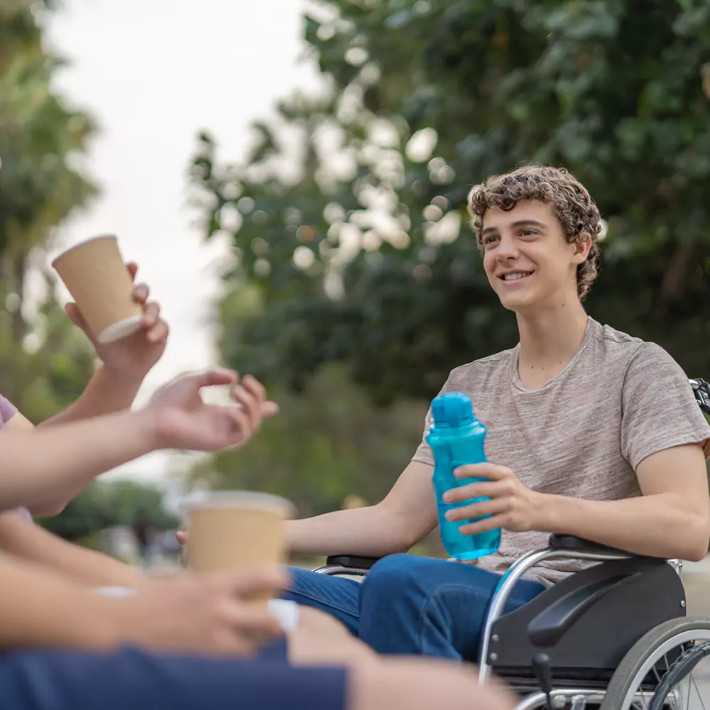 A young man in a wheelchair happily spending time with friends outside