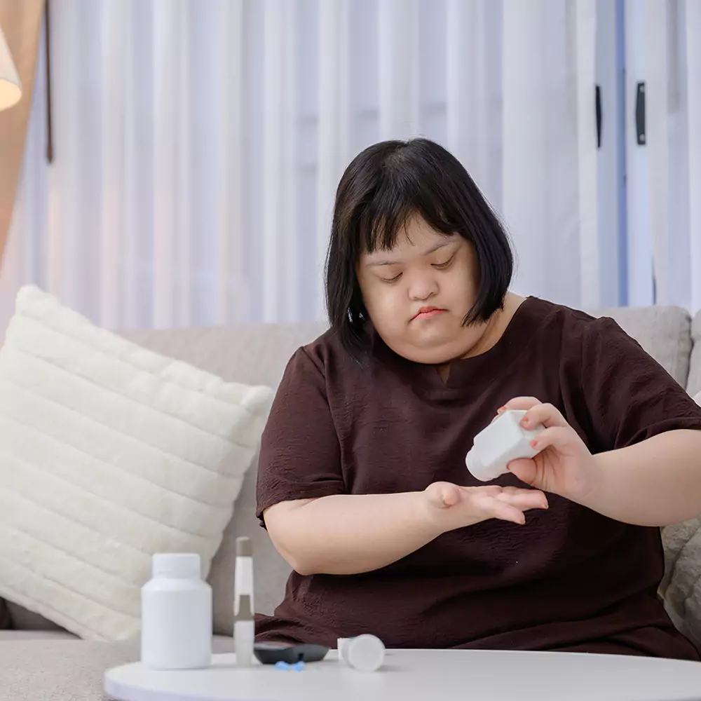 a down syndrome woman on a couch with her medication