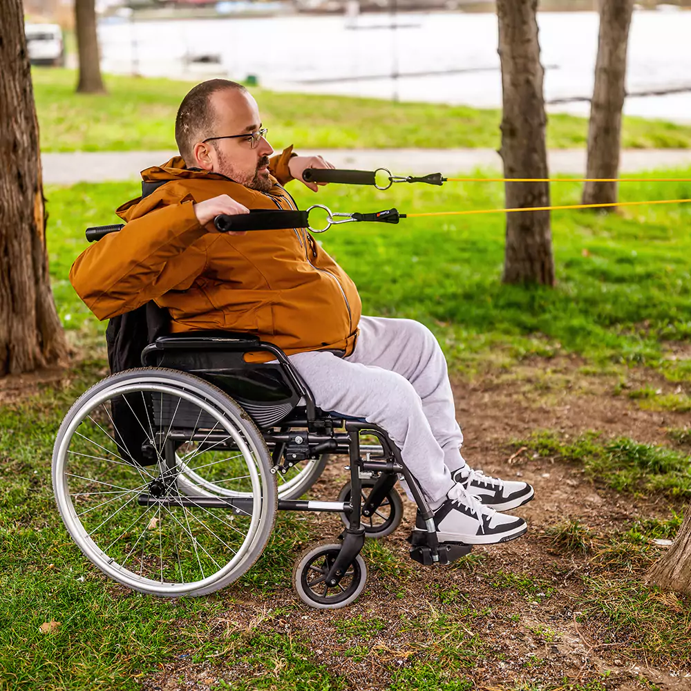 A paraplegic man in a wheelchair exercises his upper body outdoors